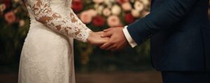 Bride and groom holding hands amid elegant floral wedding décor, symbolizing love and commitment.
