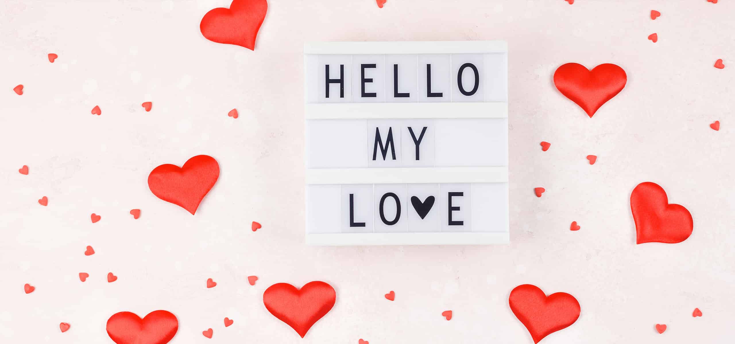 Romantic lightbox sign with red hearts and “HELLO MY LOVE” message on soft pink background.