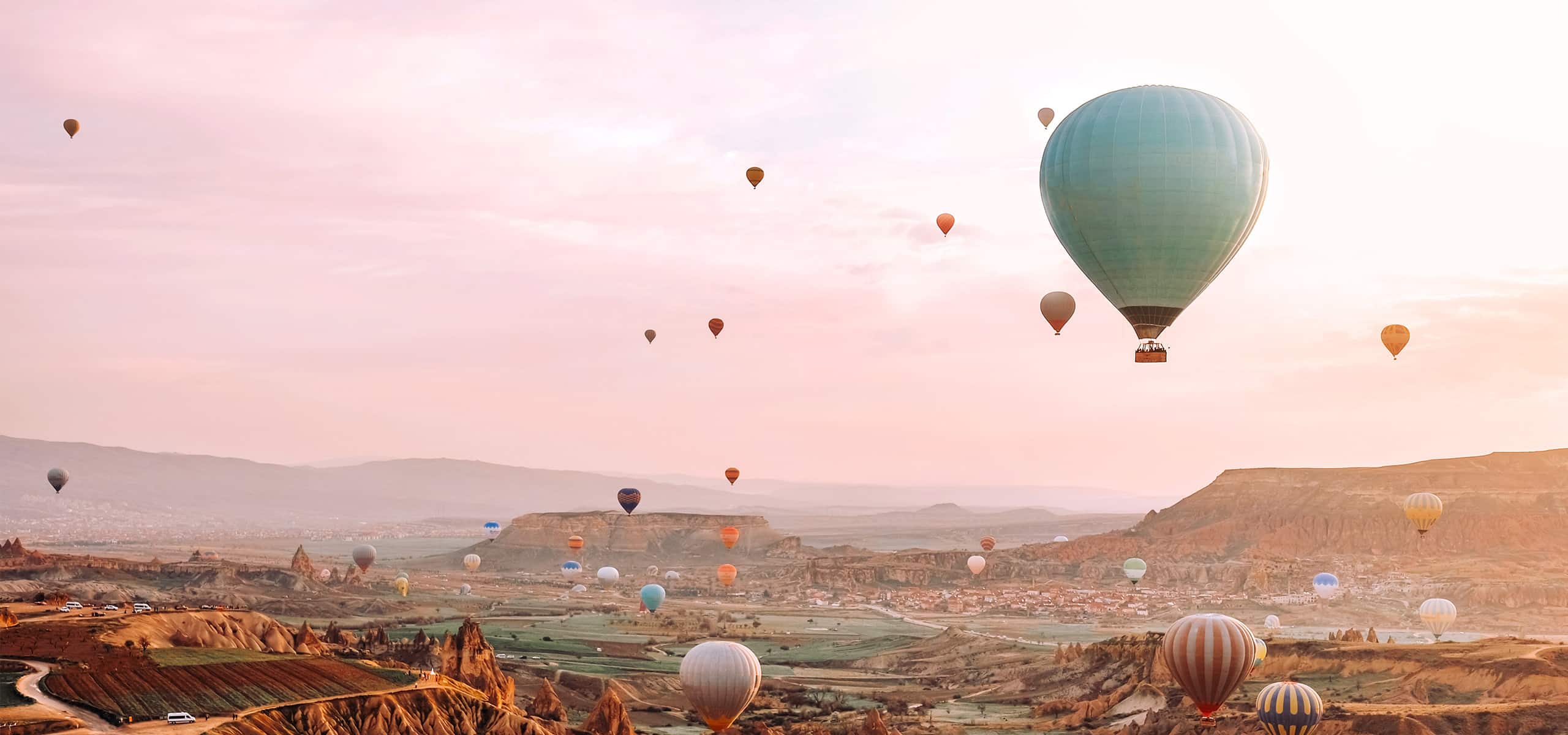 Colorful hot air balloons floating over scenic hills at sunrise, evoking romance and adventure.